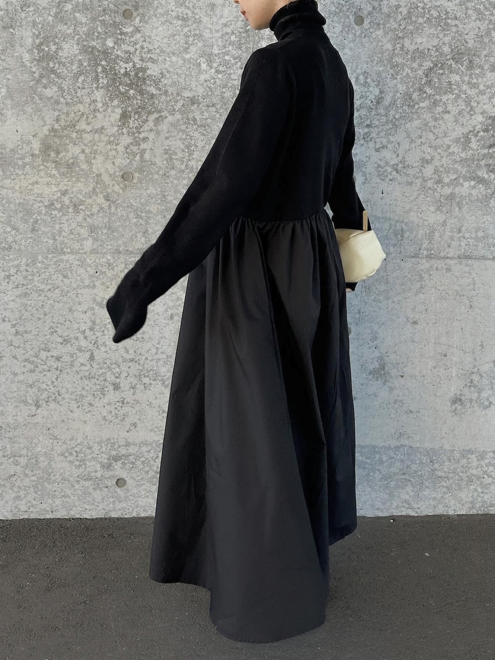 ブラック系のワンピース、ベージュ系のハンドバッグ、ブラック系のスリッポンを着用したレディースの冬コーディネートの2枚目の写真