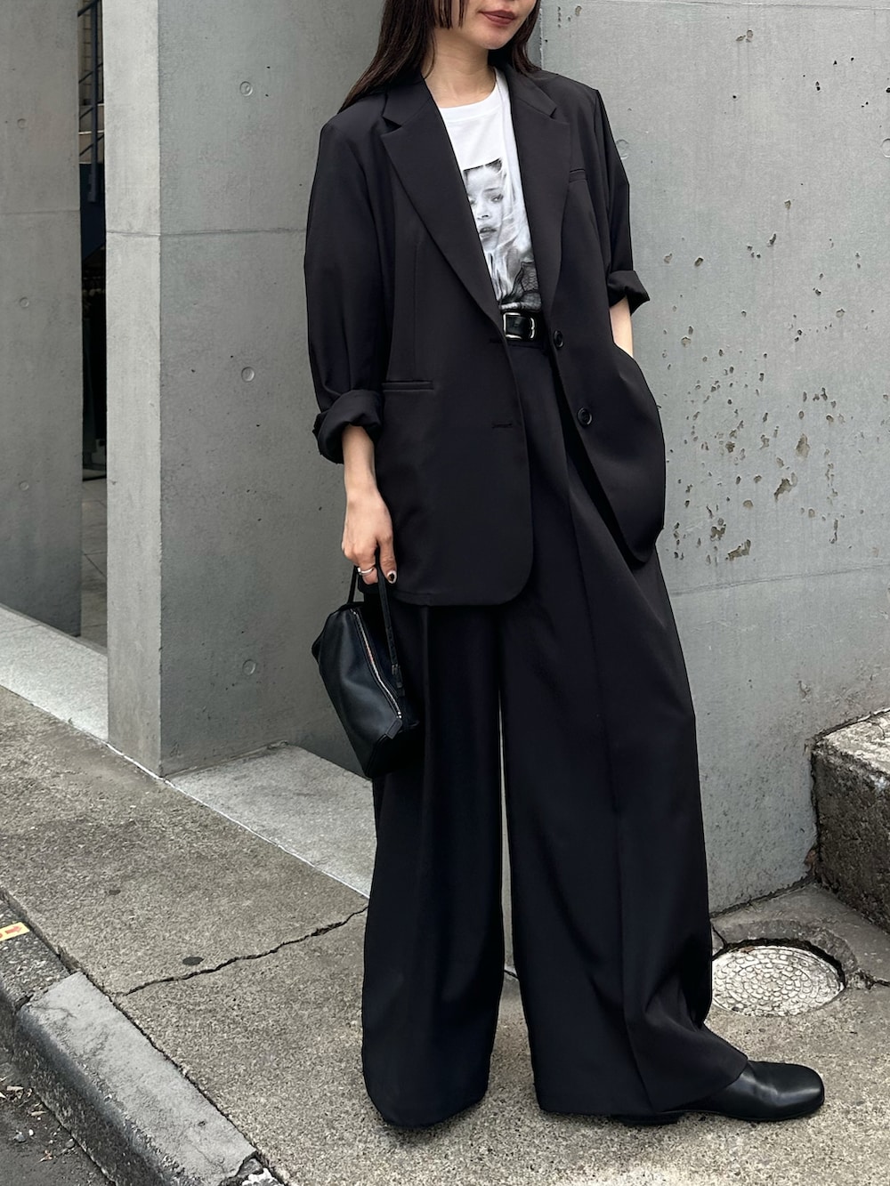 ブラック系のテーラードジャケット、ブラック系のスラックス、ホワイト系のTシャツ/カットソーを着用したレディースの春コーディネートの5枚目の写真