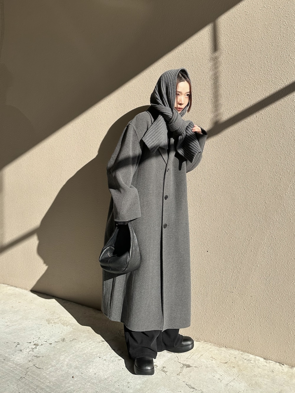 グレー系のステンカラーコート、ブラック系のローファー、ブラック系のハンドバッグを着用したレディースの冬コーディネートの2枚目の写真