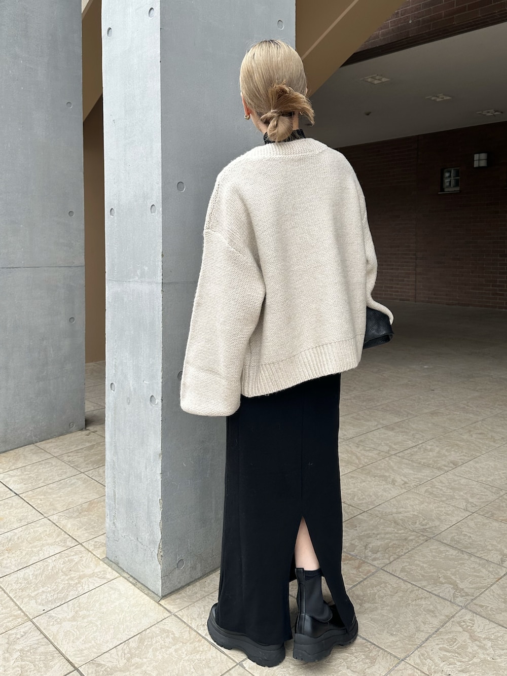 ホワイト系のカーディガン/ボレロ、ブラック系のワンピース、ブラック系のブーツを着用したレディースの秋コーディネートの5枚目の写真