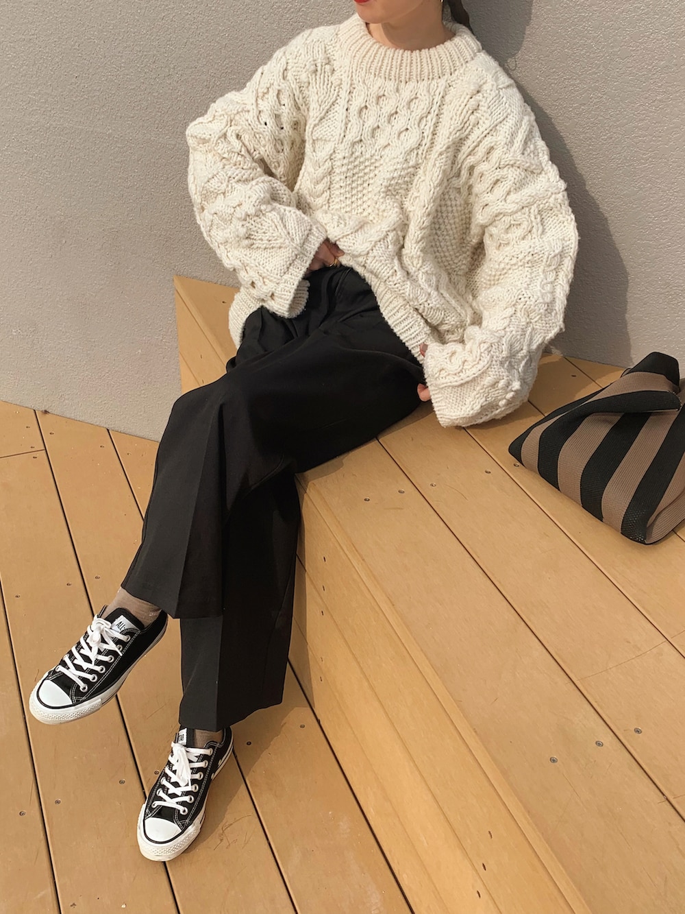 ブラック系のスラックス、ホワイト系のニット/セーター、ブラック系のスニーカーを着用したレディースの冬コーディネートの2枚目の写真