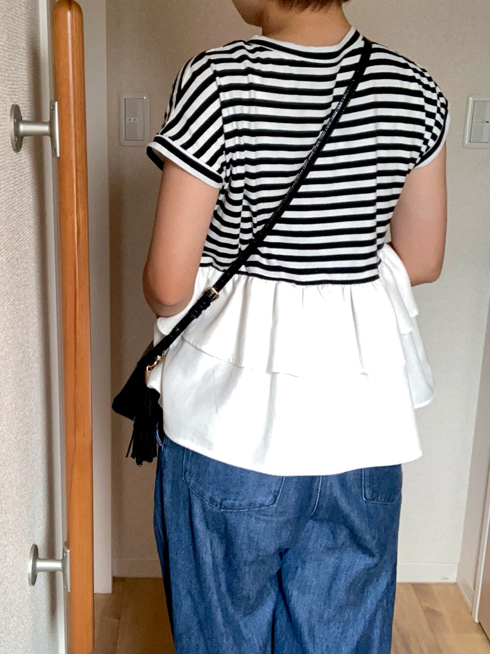 ブラック系のTシャツ/カットソー、ブラック系のショルダーバッグ、ブルー系のデニムパンツを着用したレディースの夏コーディネートの2枚目の写真