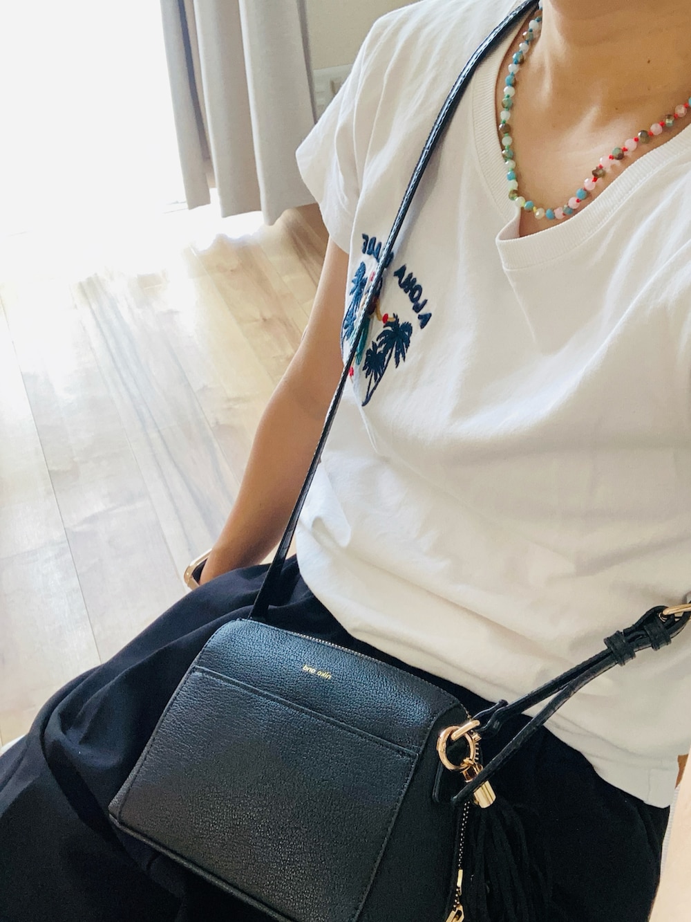 ブラック系のスラックス、ホワイト系のTシャツ/カットソー、ブラック系のショルダーバッグを着用したレディースの夏コーディネートの2枚目の写真