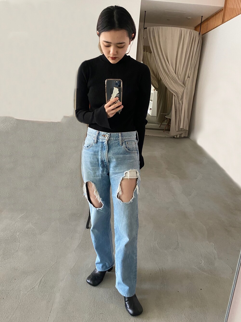 ブラック系のニット/セーター、ブルー系のデニムパンツを着用したレディースの春コーディネートの2枚目の写真