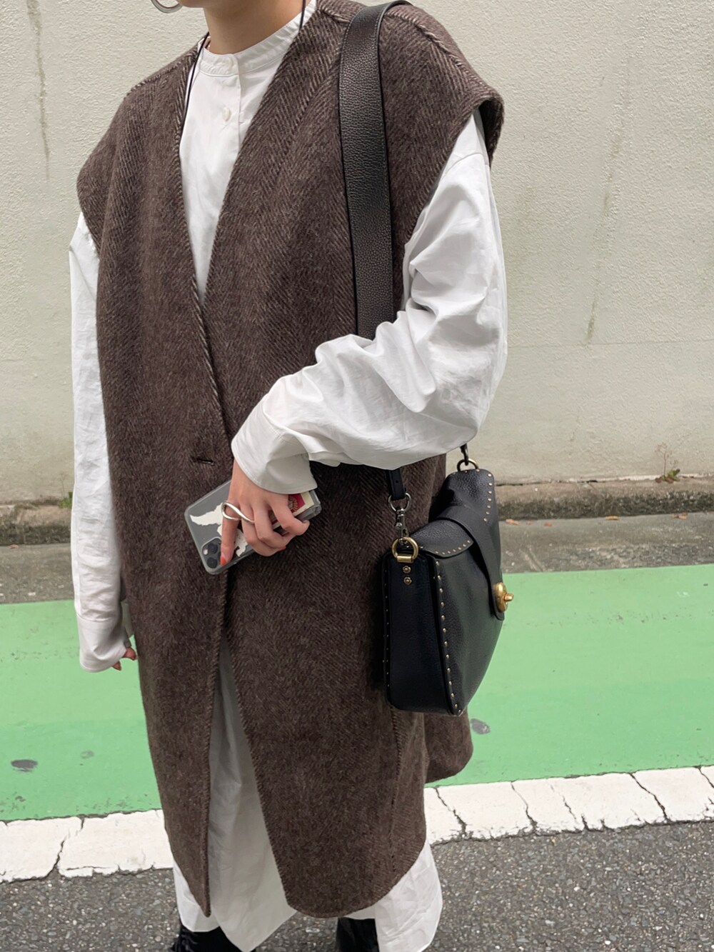 ブラウン系のベスト、ホワイト系のワンピースを着用したレディースの秋コーディネートの2枚目の写真