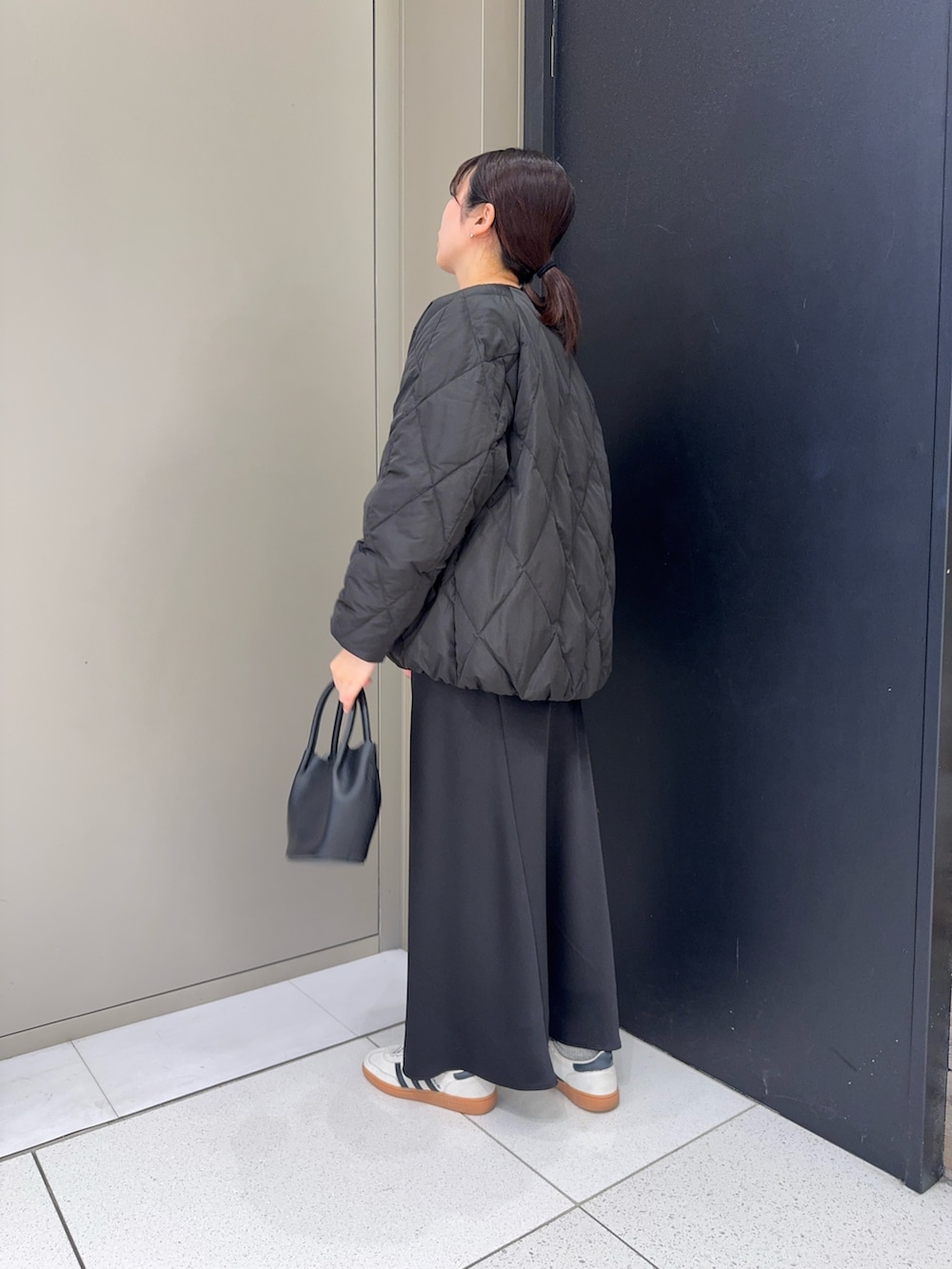 ブラック系のダウンジャケット/コート、ブラック系のスカート、ブラック系のハンドバッグを着用したレディースの冬コーディネートの2枚目の写真