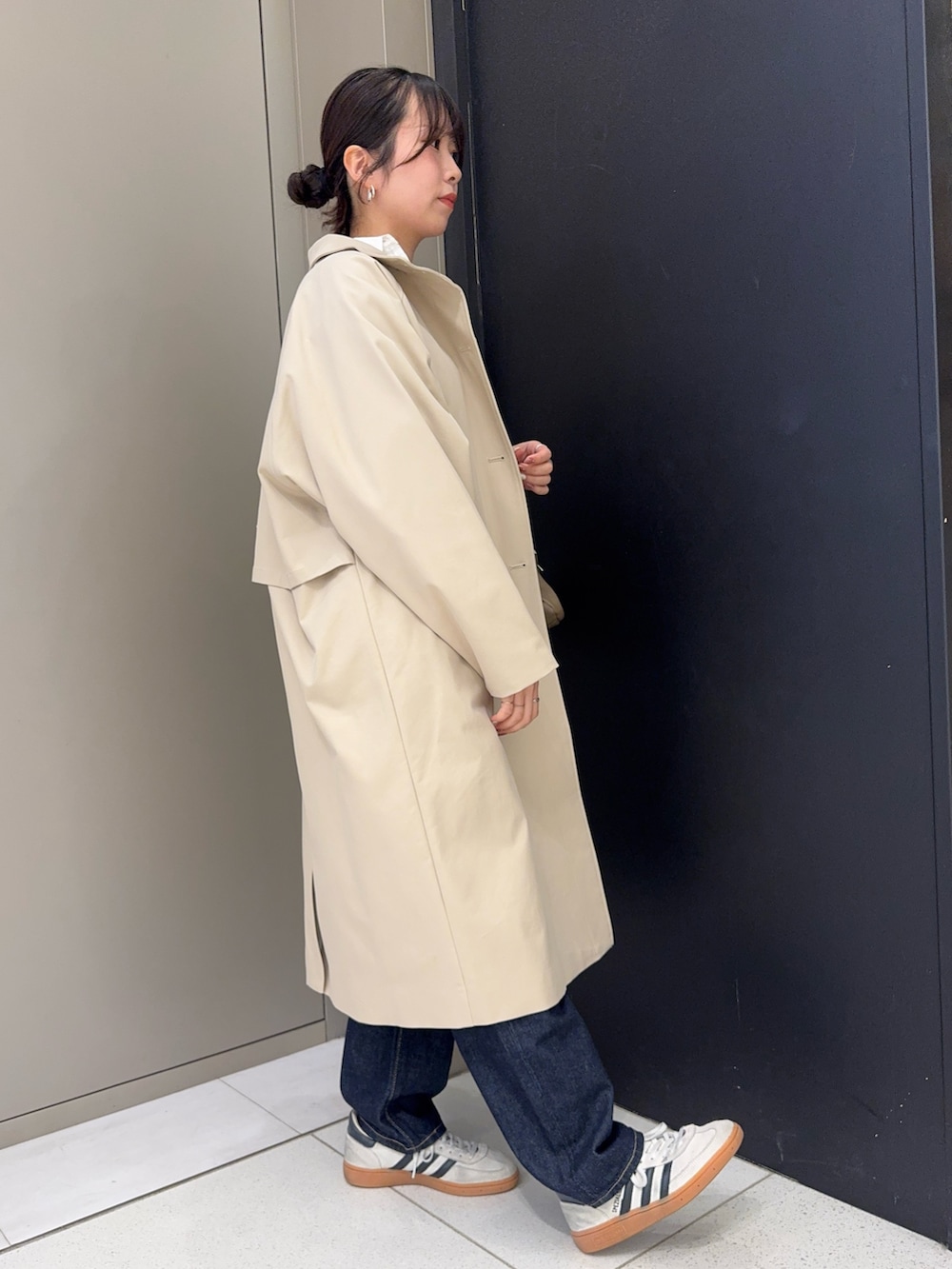 ブラウン系のハンドバッグ、ベージュ系のその他アウター、ブルー系のデニムパンツを着用したレディースの春コーディネートの2枚目の写真