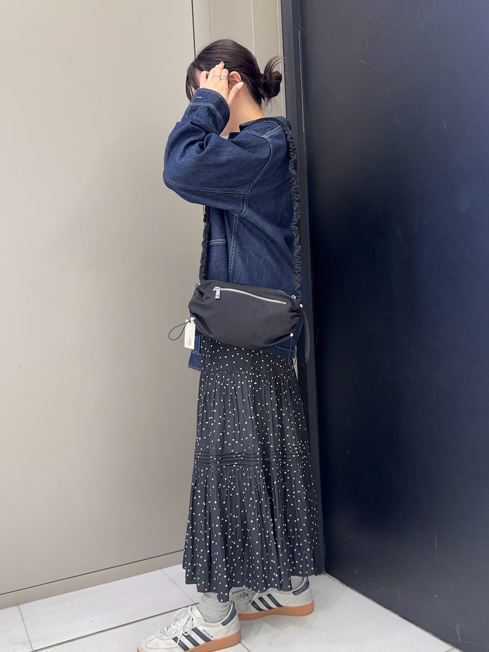 ブルー系のカバーオール、グレー系のカーディガン/ボレロ、ブラック系のスカートを着用したレディースの春コーディネートの3枚目の写真