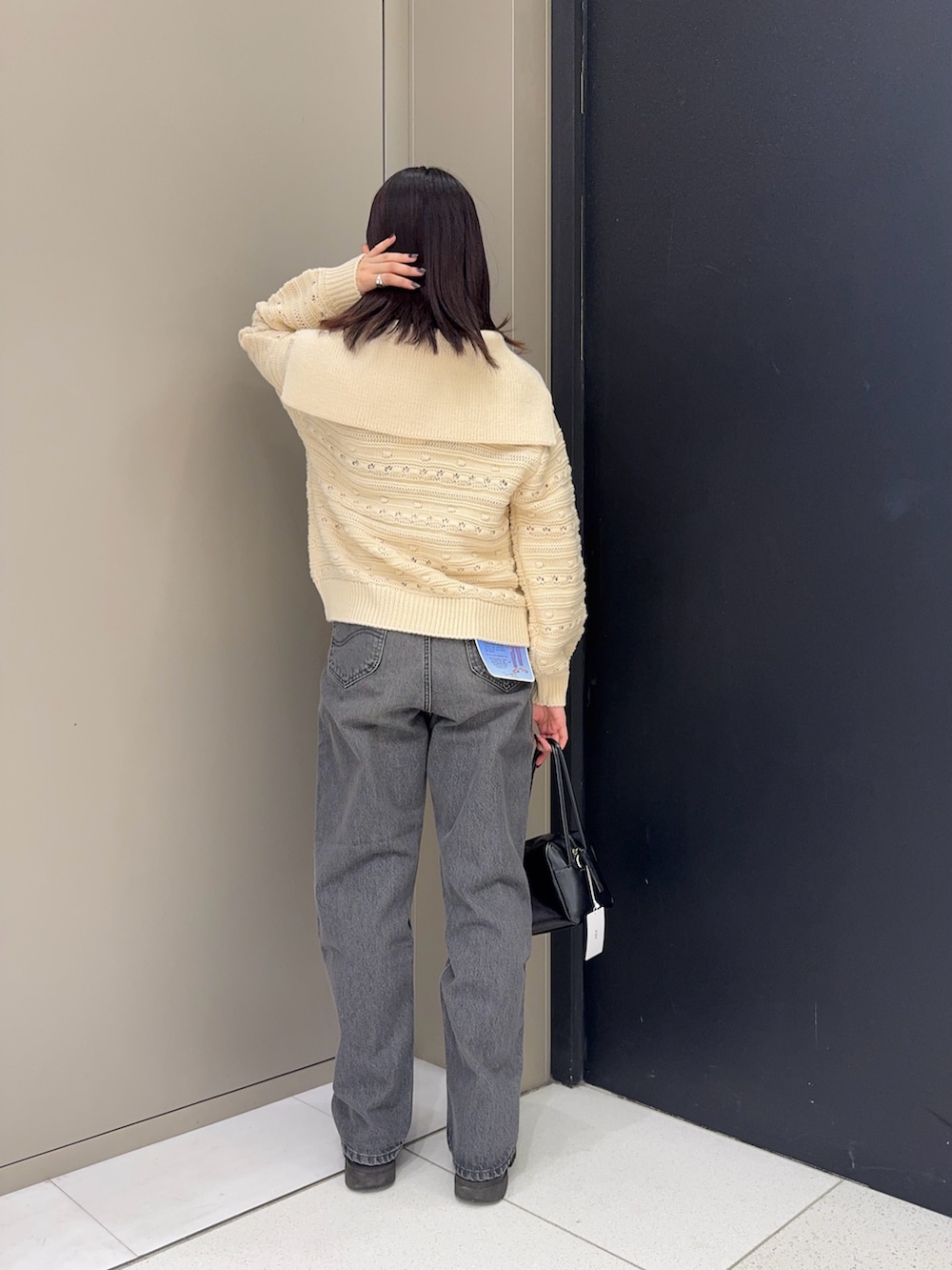 ホワイト系のニット/セーター、ブラック系のデニムパンツ、ブラック系のショルダーバッグを着用したレディースの冬コーディネートの2枚目の写真