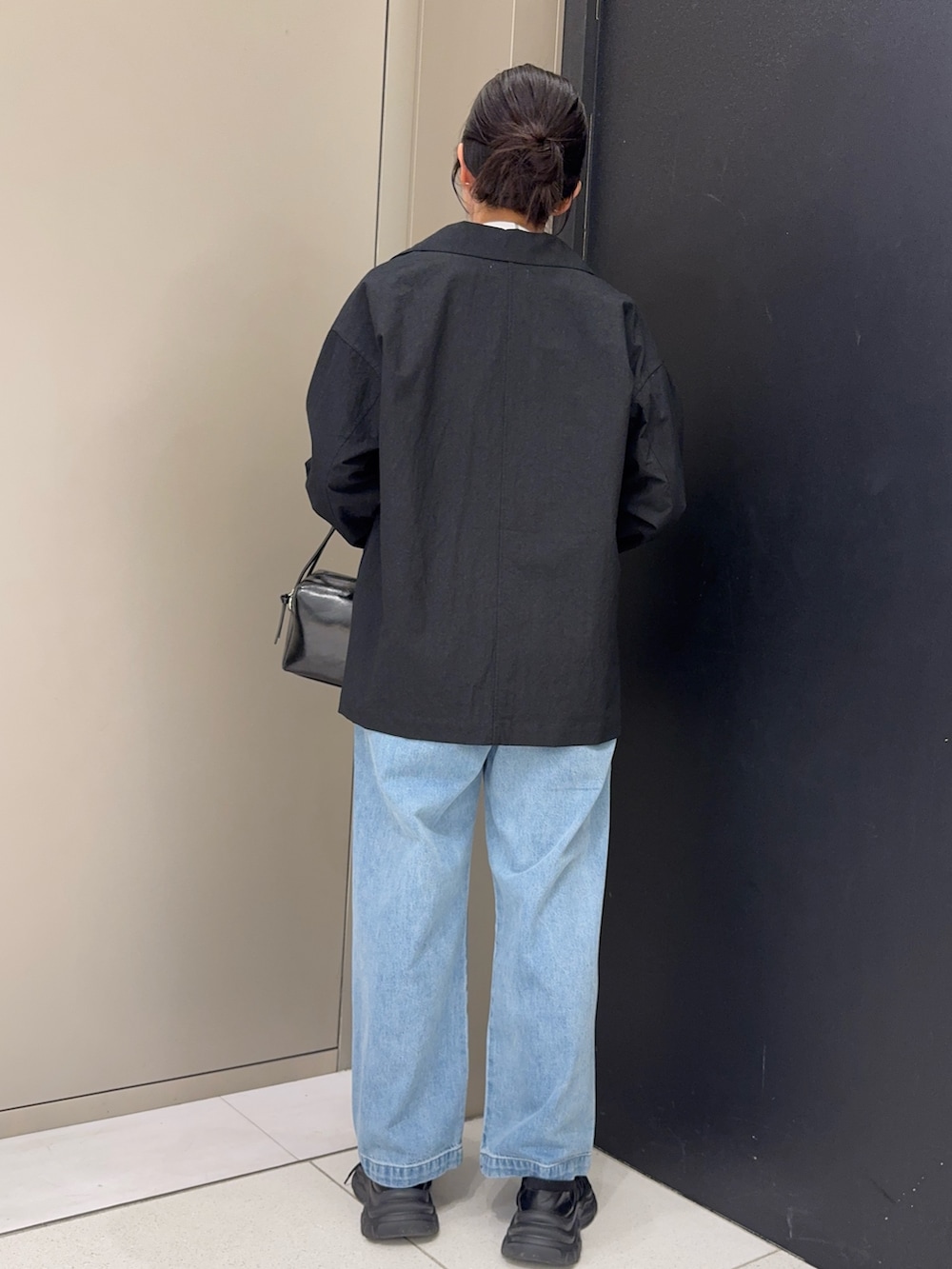 ブラック系のその他アウター、ブラック系のショルダーバッグ、ブルー系のデニムパンツを着用したレディースの春コーディネートの3枚目の写真