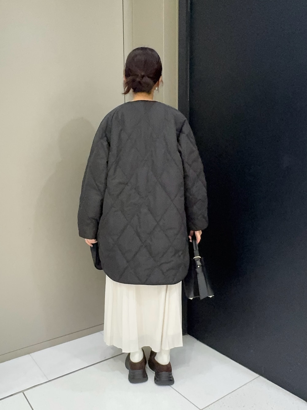 ブラック系のダウンジャケット/コート、グレー系のスカート、ブラウン系のローファーを着用したレディースの冬コーディネートの3枚目の写真