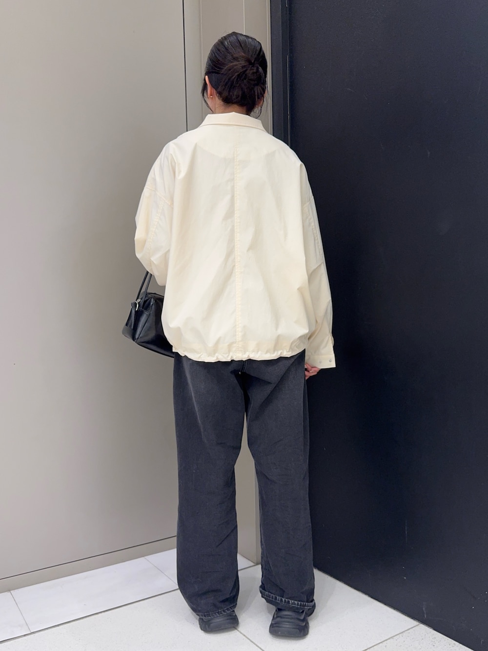 ホワイト系のブルゾン、ブラック系のデニムパンツ、ブラック系のショルダーバッグを着用したレディースの春コーディネートの3枚目の写真