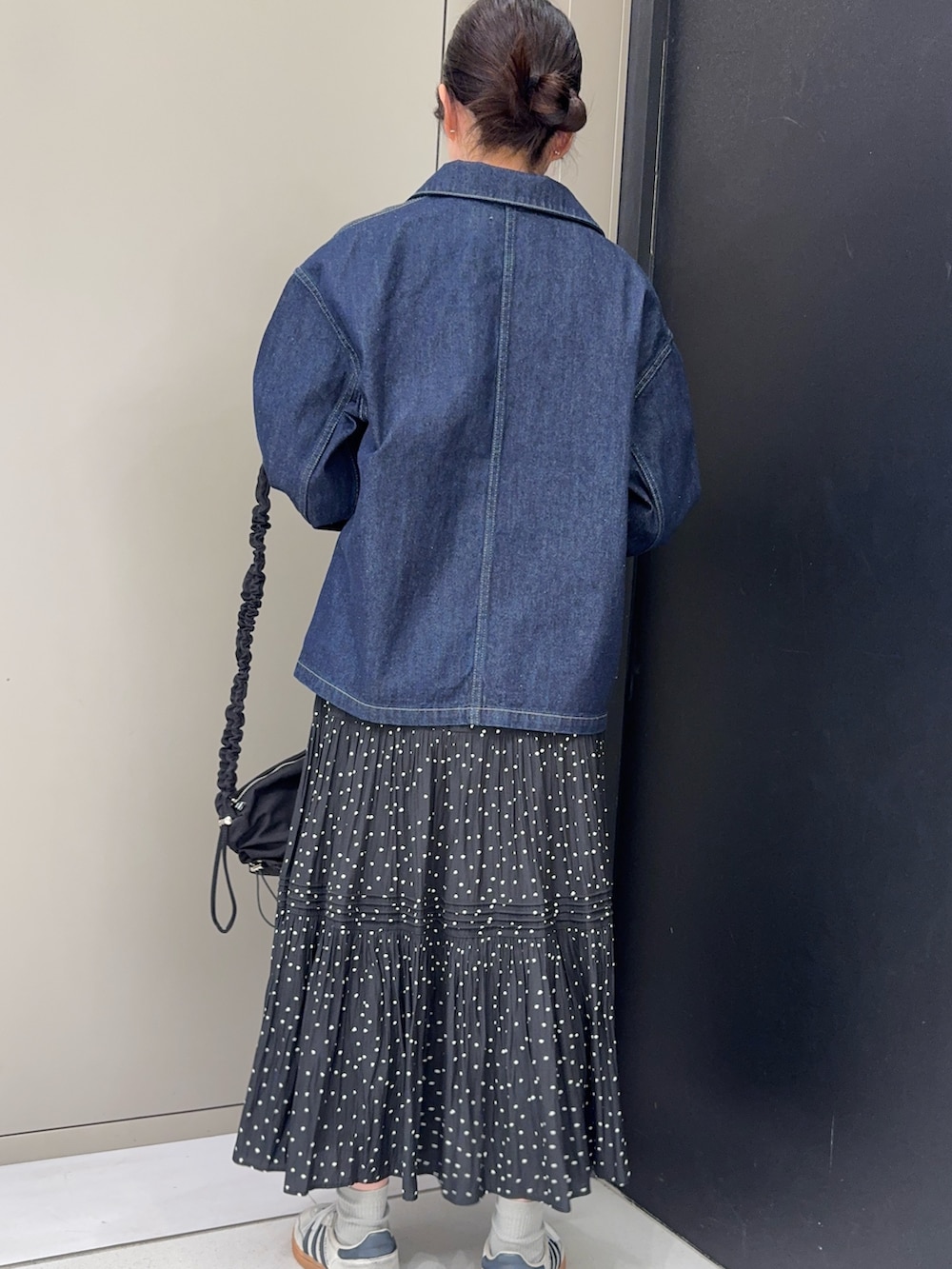 ブルー系のカバーオール、グレー系のカーディガン/ボレロ、ブラック系のスカートを着用したレディースの春コーディネートの2枚目の写真