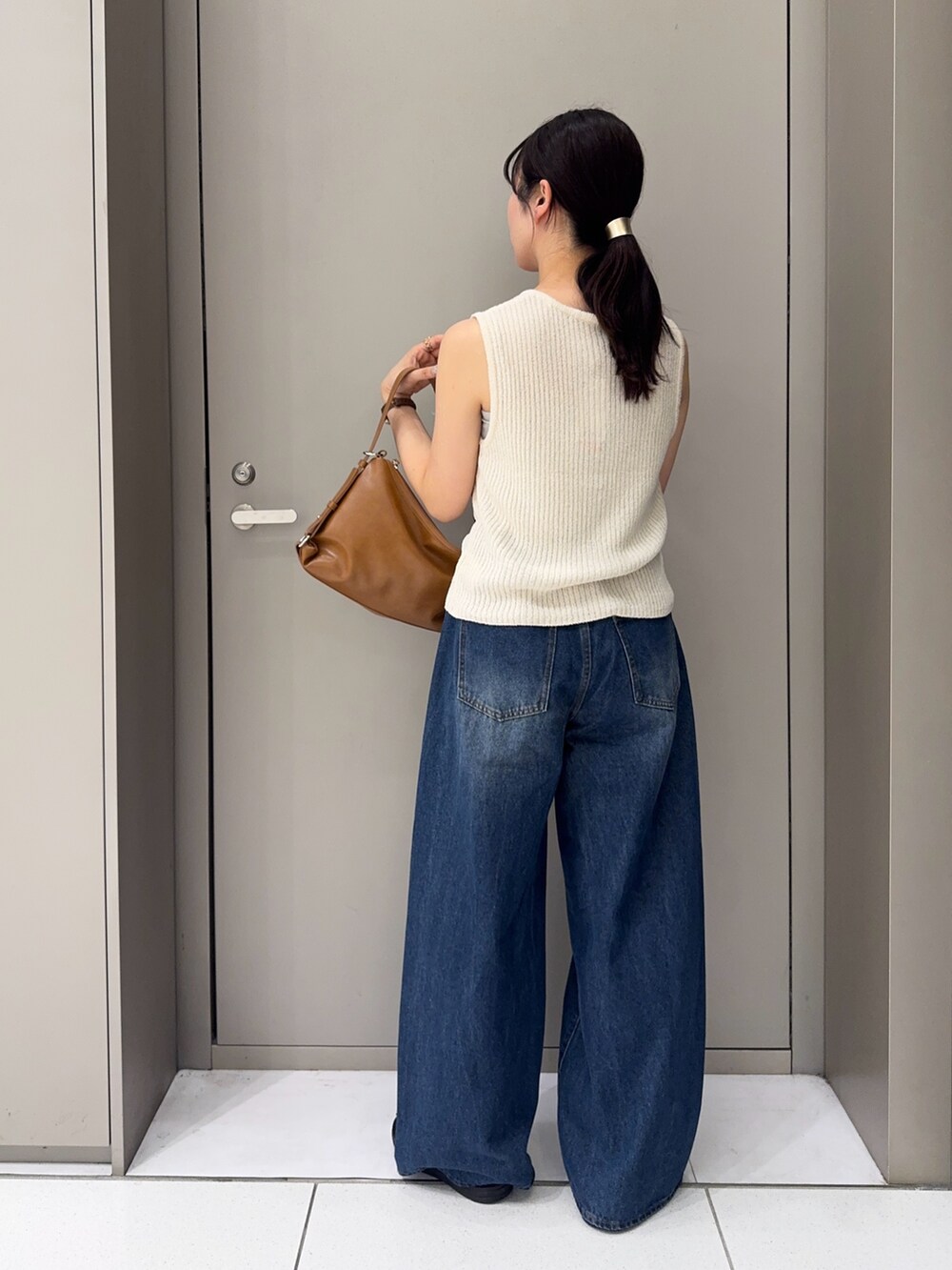 ブルー系のデニムパンツ、ブラック系のサンダル、イエロー系のショルダーバッグを着用したレディースの夏コーディネートの3枚目の写真