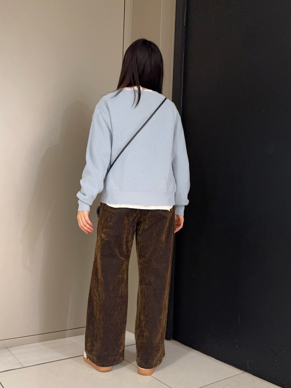 ブラウン系のデニムパンツ、ホワイト系のTシャツ/カットソー、ブルー系のニット/セーターを着用したレディースの冬コーディネートの3枚目の写真