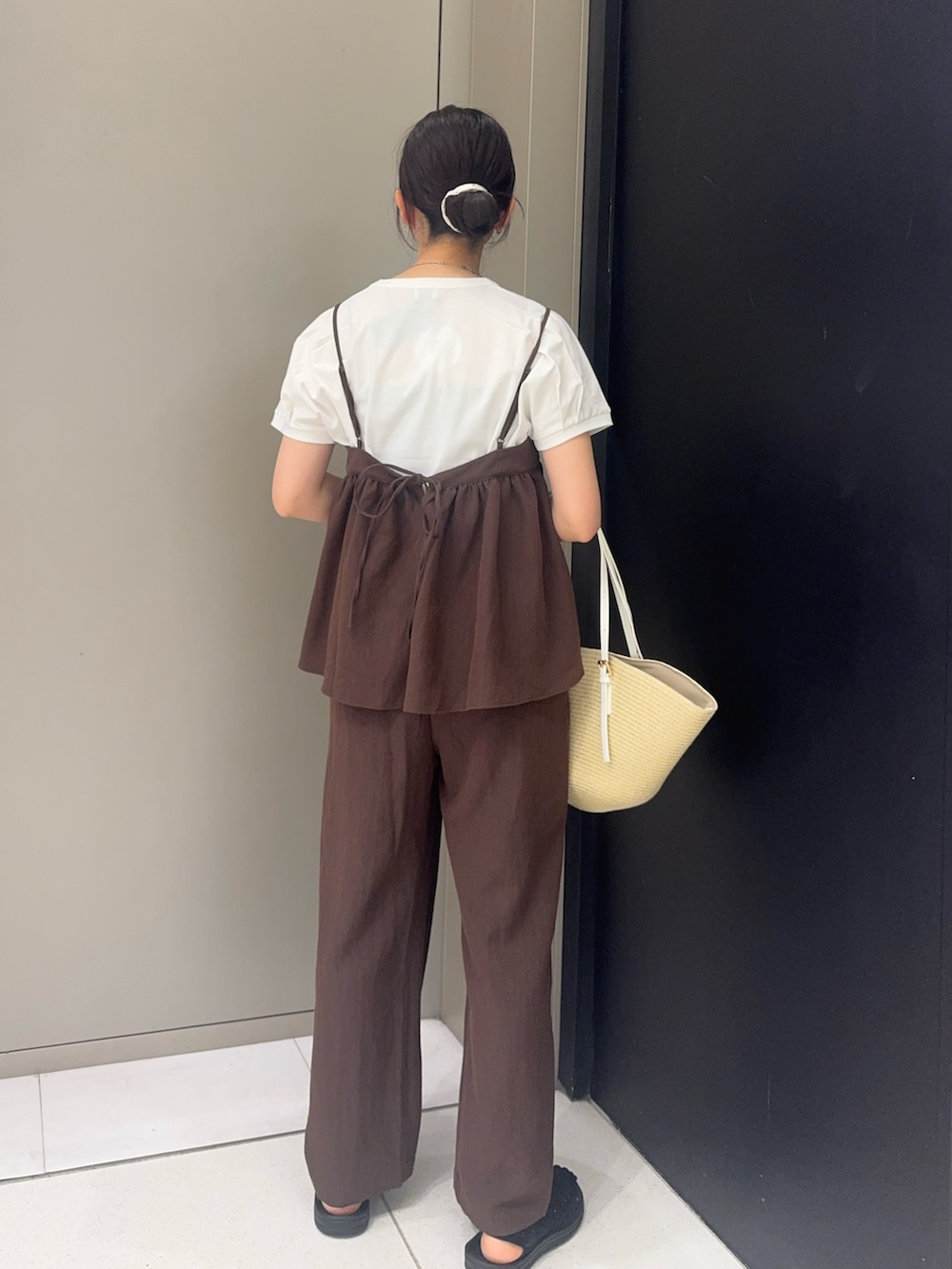 ブラック系のサンダル、ブラウン系のパンツ、ベージュ系のかごバッグを着用したレディースの夏コーディネートの3枚目の写真