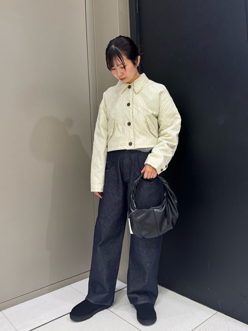 ホワイト系のダウンジャケット/コート、ブラック系のハンドバッグ、ブルー系のデニムパンツを着用したレディースの秋コーディネートの2枚目の写真