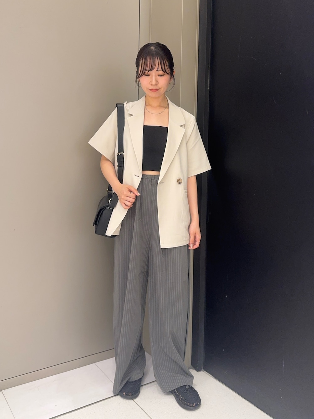 ホワイト系のセットアップ、グレー系のその他パンツ、ブラック系のサンダルを着用したレディースの夏コーディネートの3枚目の写真