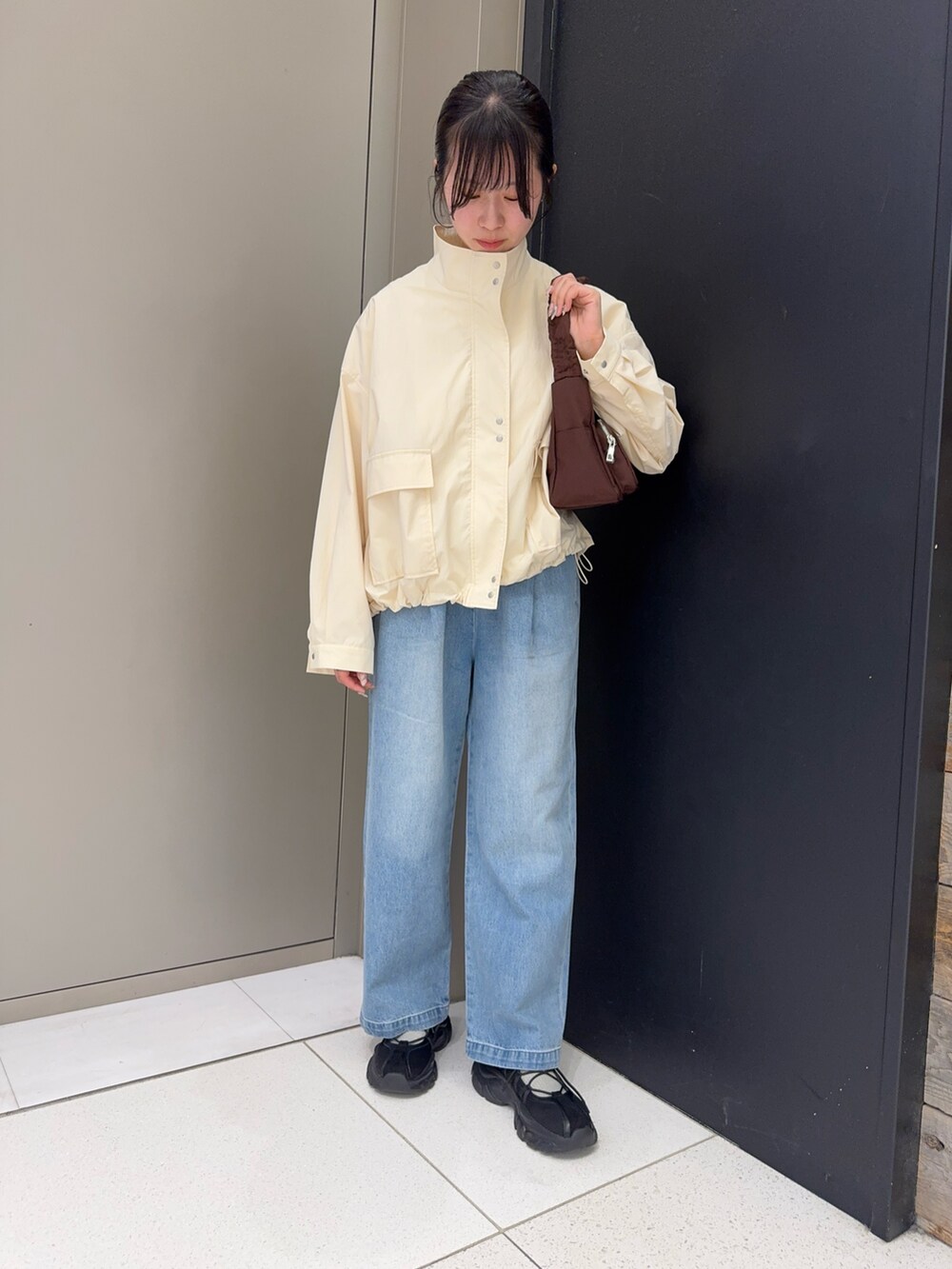 レッド系のTシャツ/カットソー、ホワイト系のブルゾン、ブルー系のデニムパンツを着用したレディースの春コーディネートの2枚目の写真