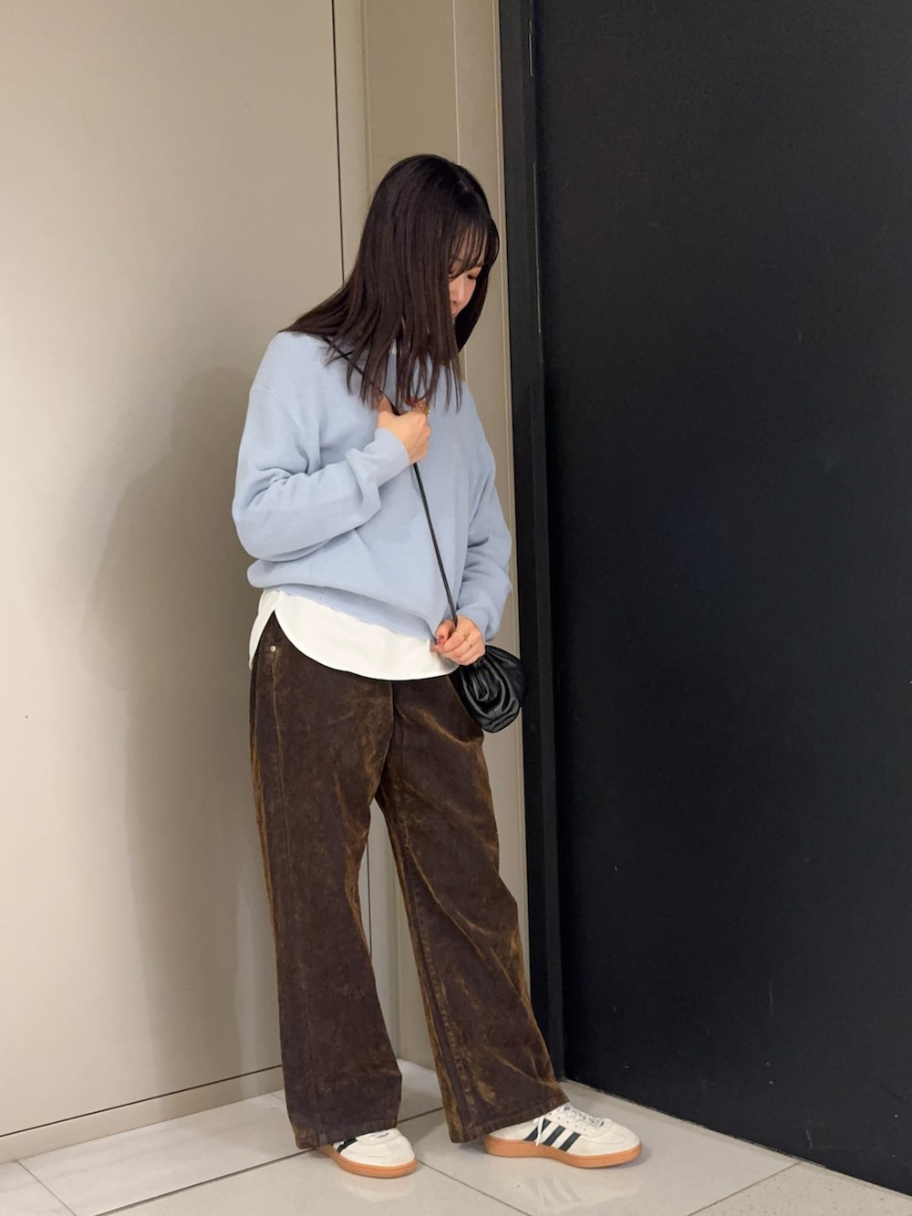 ブラウン系のデニムパンツ、ホワイト系のTシャツ/カットソー、ブルー系のニット/セーターを着用したレディースの冬コーディネートの2枚目の写真