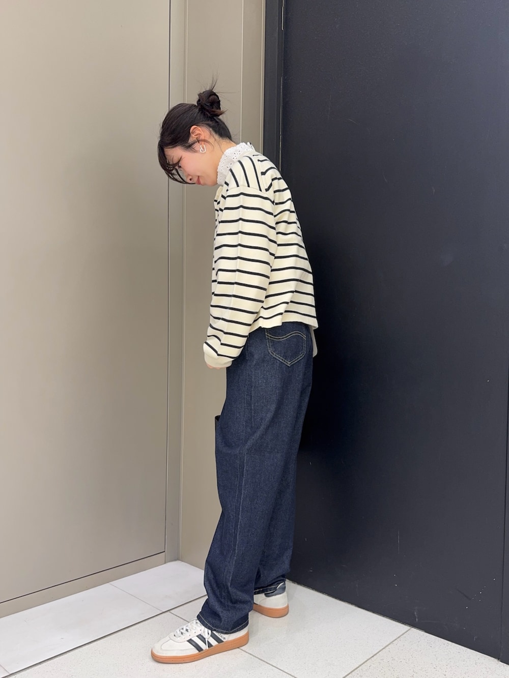 ブラック系のハンドバッグ、ブルー系のデニムパンツ、ホワイト系のカーディガン/ボレロを着用したレディースの冬コーディネートの2枚目の写真