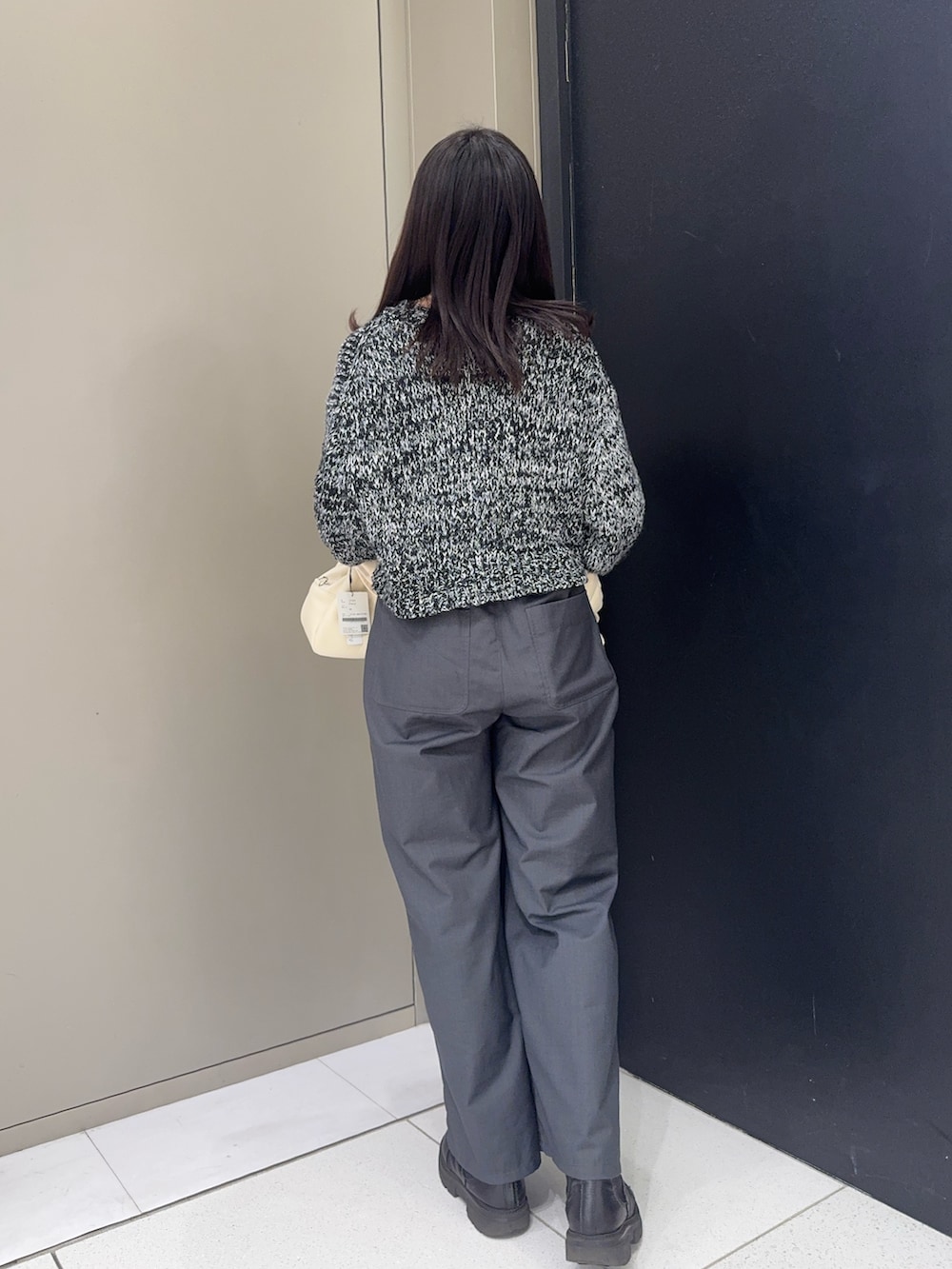 ブラック系のニット/セーター、ホワイト系のハンドバッグを着用したレディースの冬コーディネートの2枚目の写真