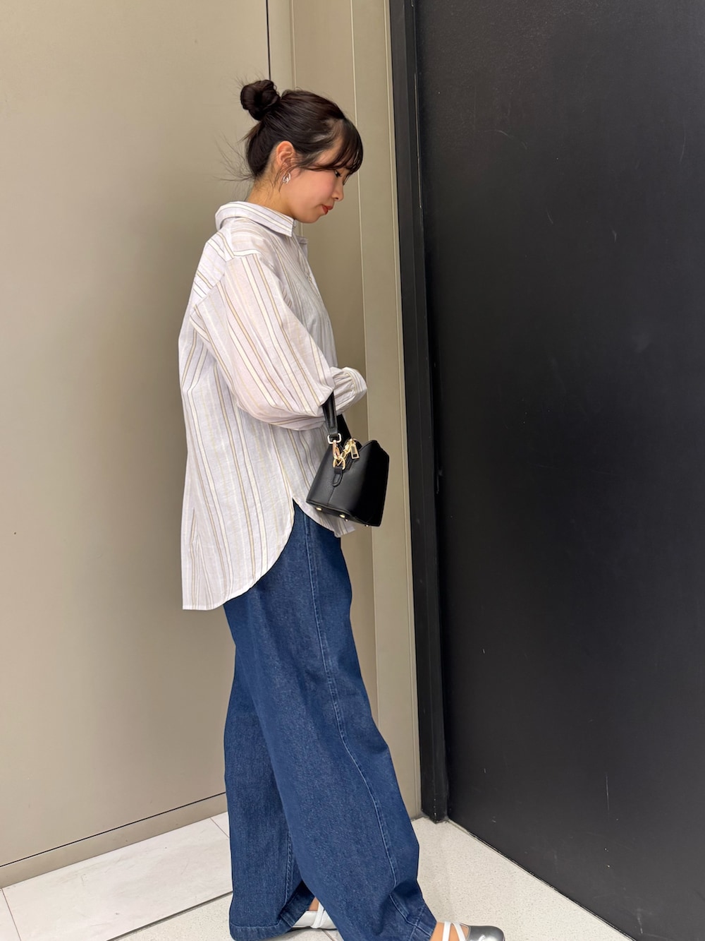 ブラック系のショルダーバッグ、パープル系のシャツ/ブラウス、ブルー系のデニムパンツを着用したレディースの春コーディネートの2枚目の写真