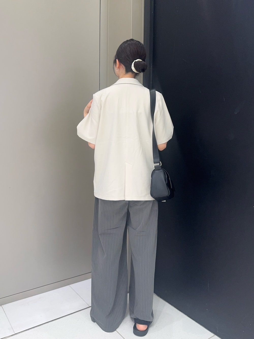 ホワイト系のセットアップ、グレー系のその他パンツ、ブラック系のサンダルを着用したレディースの夏コーディネートの2枚目の写真