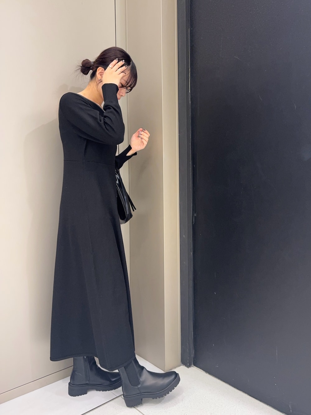 ブラック系のワンピース、ブラック系のブーツ、ブラック系のハンドバッグを着用したレディースの冬コーディネートの2枚目の写真