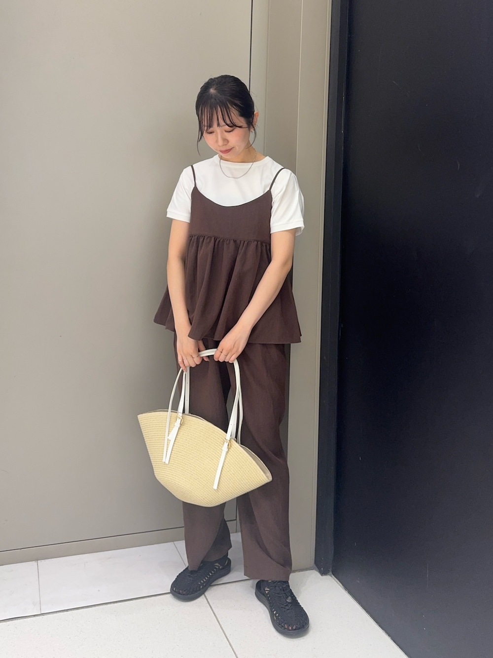 ブラック系のサンダル、ブラウン系のパンツ、ベージュ系のかごバッグを着用したレディースの夏コーディネートの4枚目の写真