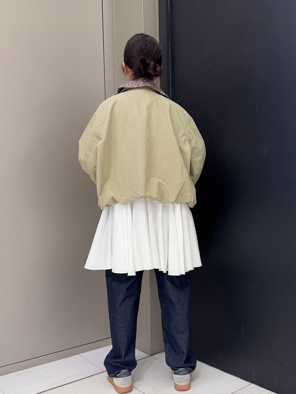 ベージュ系のブルゾン、ホワイト系のワンピース、ブルー系のデニムパンツを着用したレディースの春コーディネートの3枚目の写真