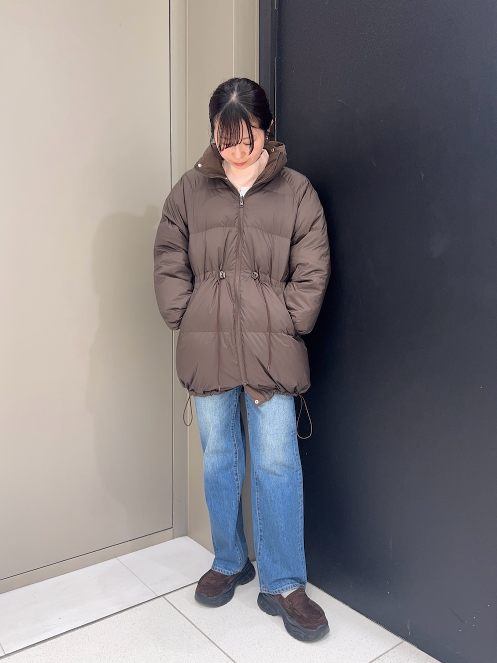 ブラウン系のダウンジャケット/コート、ブルー系のデニムパンツ、ブラウン系のローファーを着用したレディースの冬コーディネートの4枚目の写真