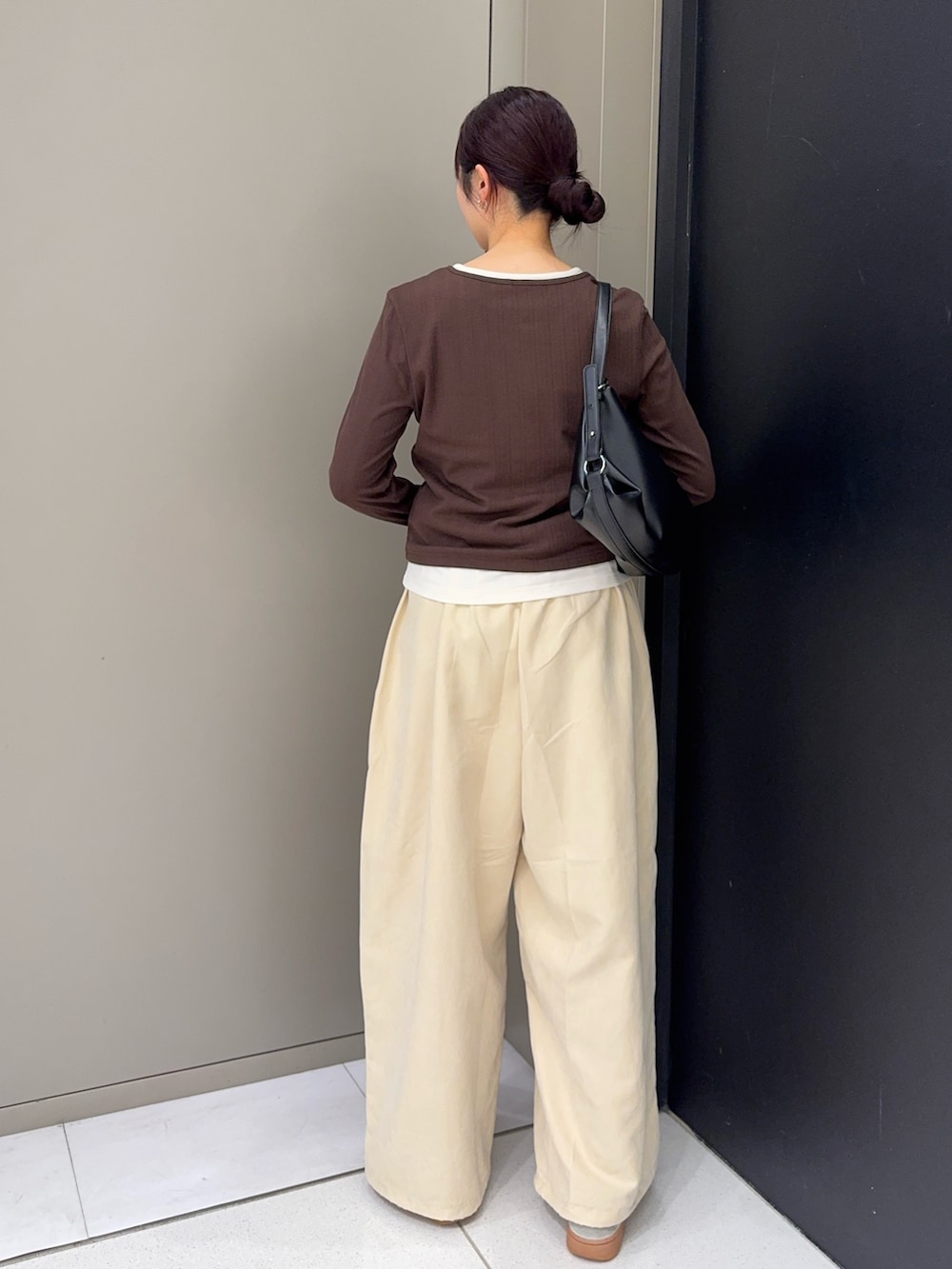 ベージュ系のその他パンツ、ホワイト系のスニーカー、ブラック系のショルダーバッグを着用したレディースの秋コーディネートの2枚目の写真