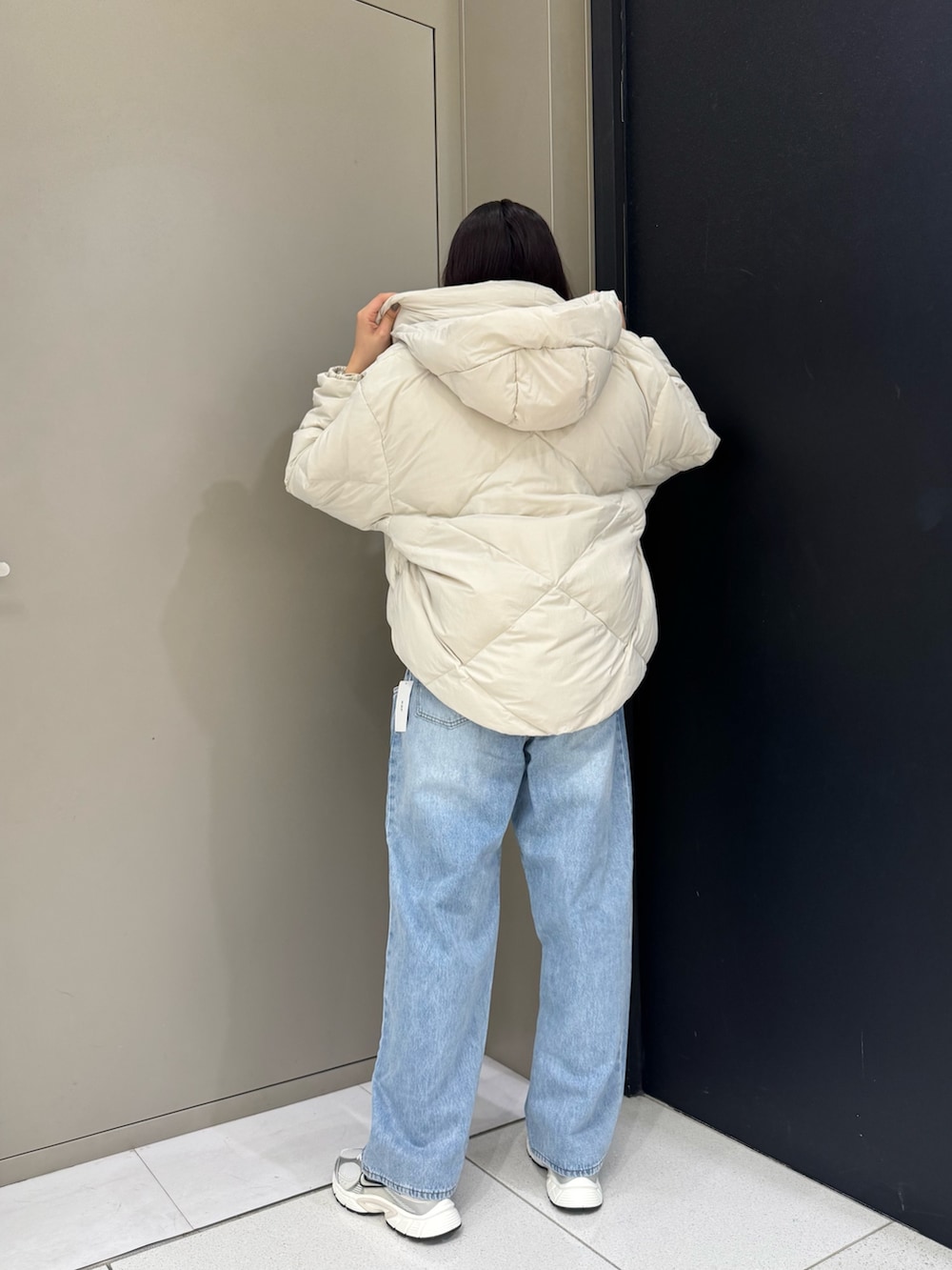 ホワイト系のダウンジャケット/コート、ブルー系のデニムパンツ、ホワイト系のスニーカーを着用したレディースの秋コーディネートの2枚目の写真