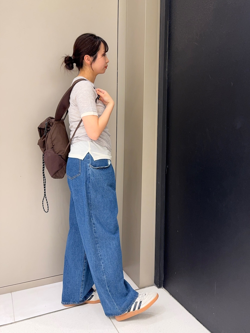 ブラウン系のバックパック/リュック、グレー系のTシャツ/カットソー、ブルー系のデニムパンツを着用したレディースの春コーディネートの2枚目の写真