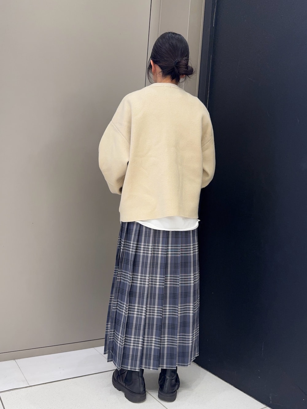 ベージュ系のニット/セーター、ホワイト系のTシャツ/カットソー、グレー系のスカートを着用したレディースの冬コーディネートの2枚目の写真