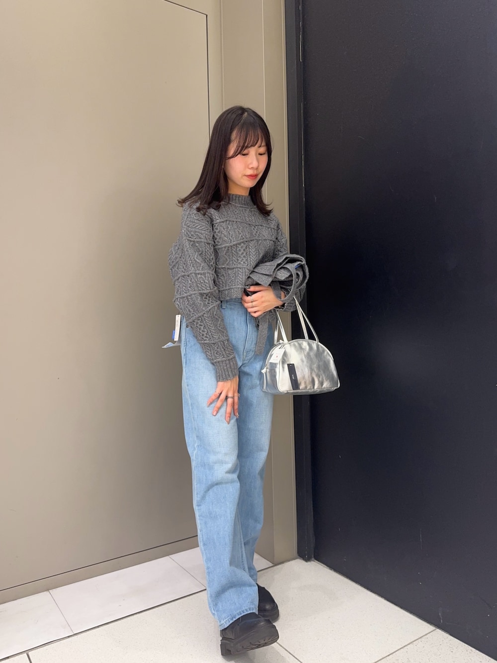 グレー系のニット/セーター、グレー系のスカート、シルバー系のボストンバッグを着用したレディースの冬コーディネートの4枚目の写真