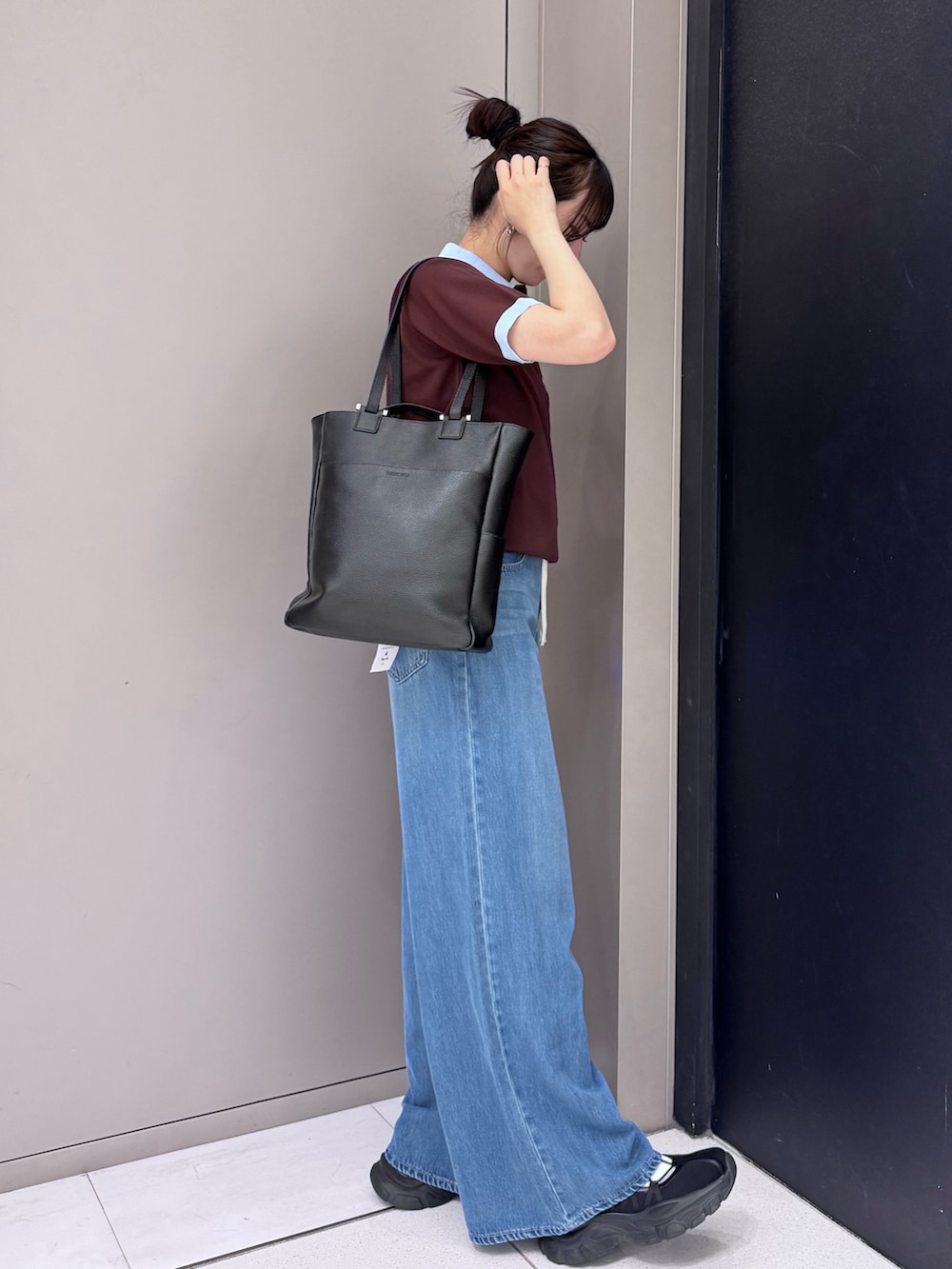 ブラウン系のニット/セーター、ブルー系のデニムパンツ、ブラック系のトートバッグを着用したレディースの春コーディネートの2枚目の写真