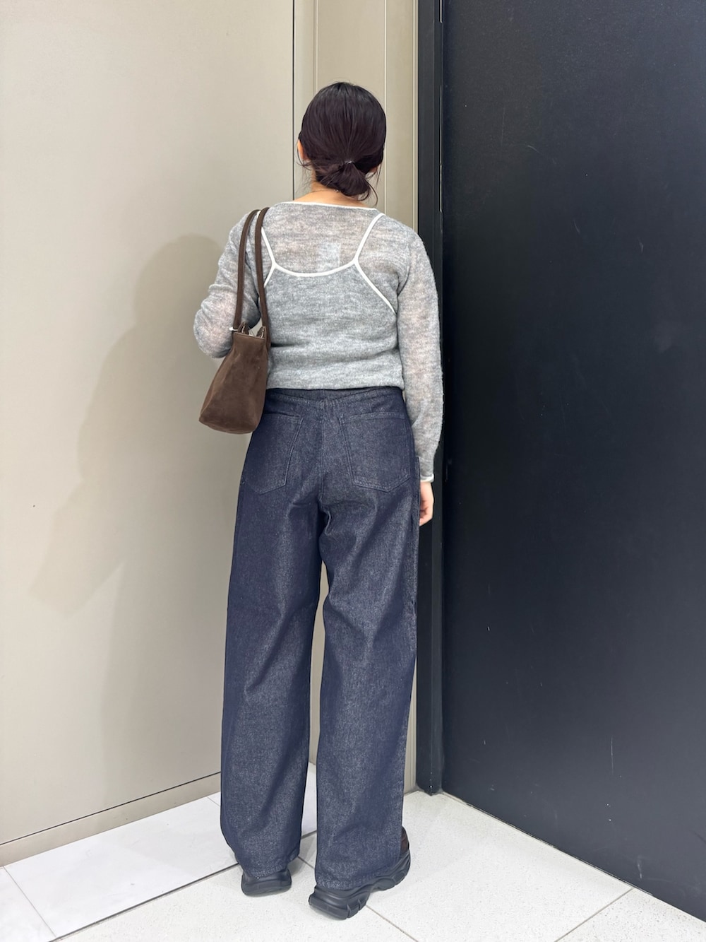 グレー系のニット/セーター、ブラウン系のボストンバッグ、ブルー系のデニムパンツを着用したレディースの秋コーディネートの4枚目の写真