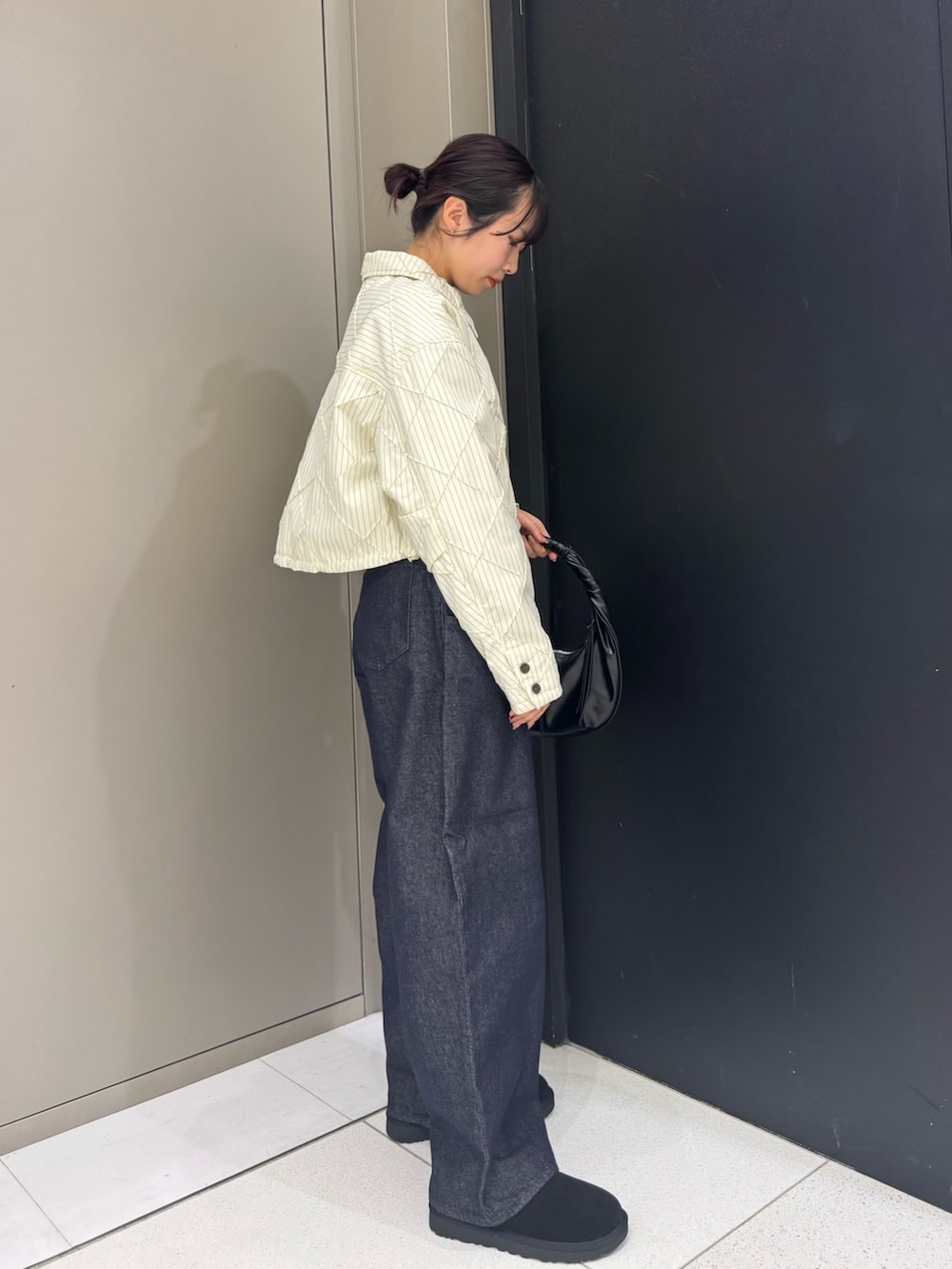 ホワイト系のダウンジャケット/コート、ブラック系のハンドバッグ、ブルー系のデニムパンツを着用したレディースの秋コーディネートの3枚目の写真