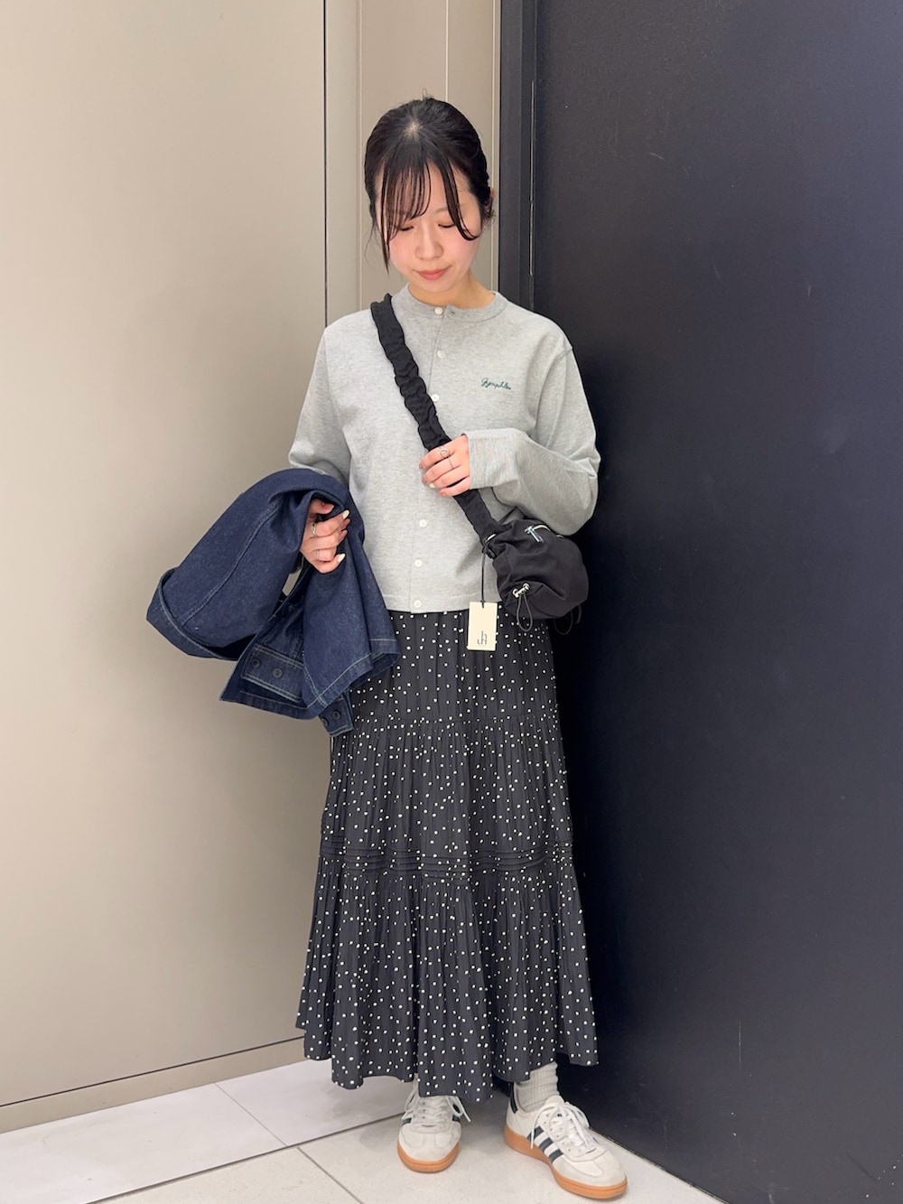 ブルー系のカバーオール、グレー系のカーディガン/ボレロ、ブラック系のスカートを着用したレディースの春コーディネートの4枚目の写真