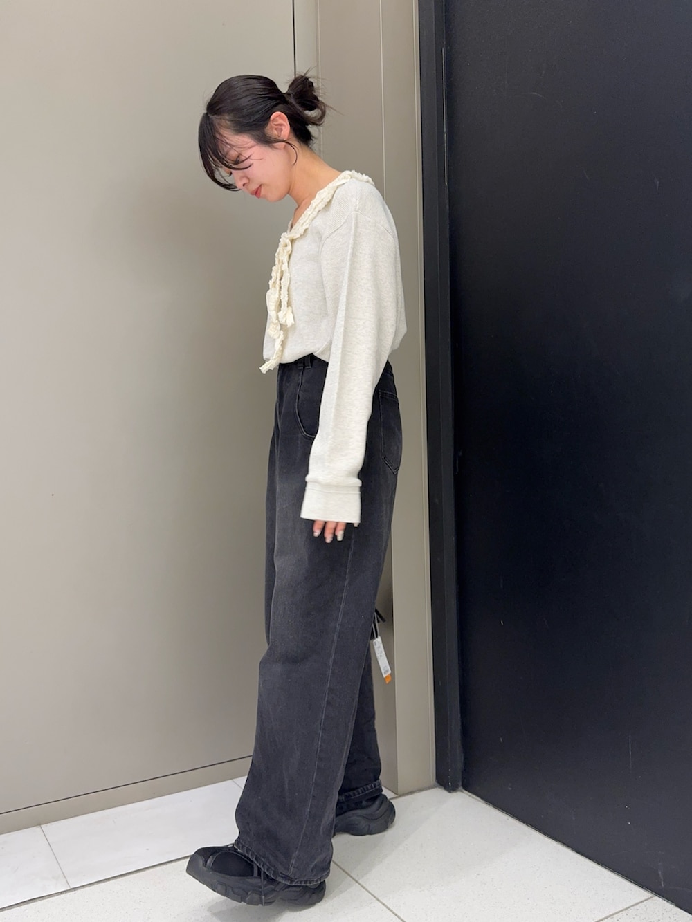 ベージュ系のTシャツ/カットソー、ブラック系のデニムパンツ、ブラック系のスニーカーを着用したレディースの春コーディネートの2枚目の写真