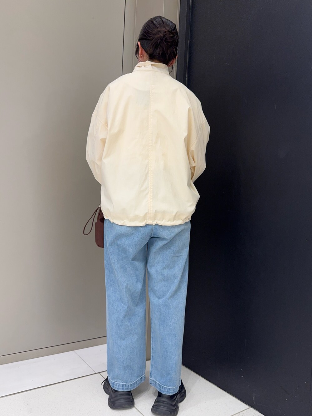 レッド系のTシャツ/カットソー、ホワイト系のブルゾン、ブルー系のデニムパンツを着用したレディースの春コーディネートの4枚目の写真