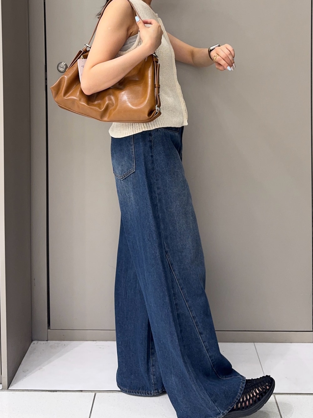 ブルー系のデニムパンツ、ブラック系のサンダル、イエロー系のショルダーバッグを着用したレディースの夏コーディネートの2枚目の写真