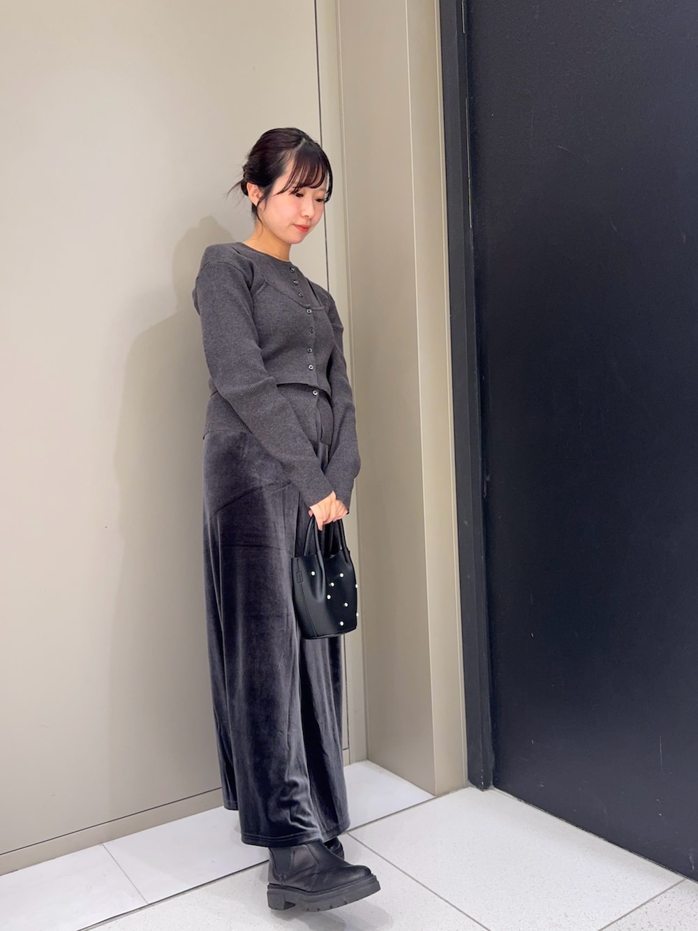 グレー系のニット/セーター、ブラック系のハンドバッグ、グレー系のスカートを着用したレディースの秋コーディネートの2枚目の写真