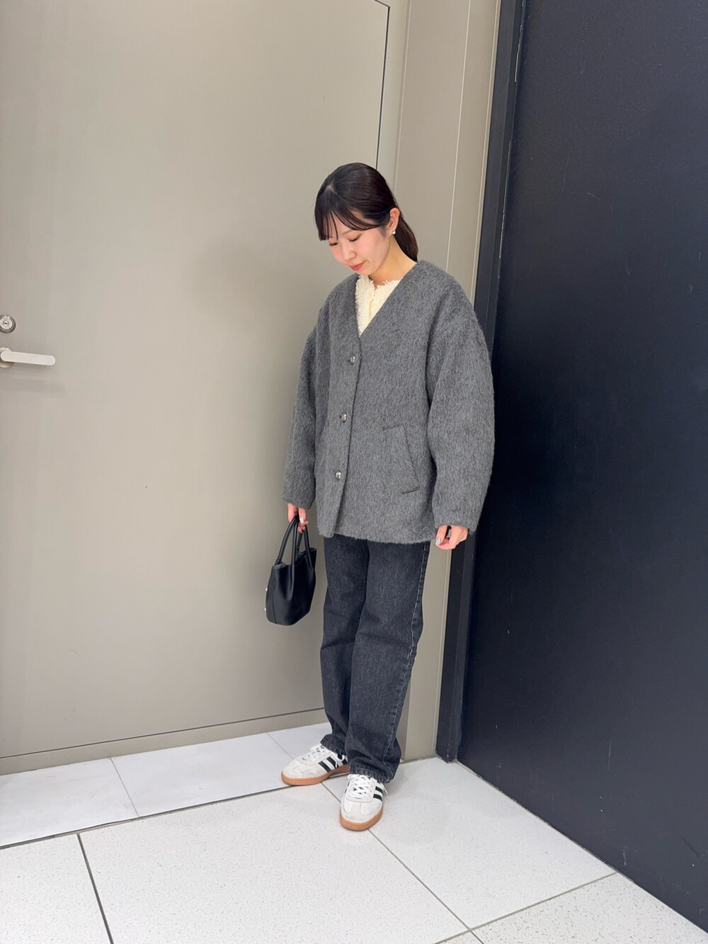 ブラック系のデニムパンツ、ブラック系のハンドバッグ、グレー系のノーカラージャケットを着用したレディースの冬コーディネートの2枚目の写真