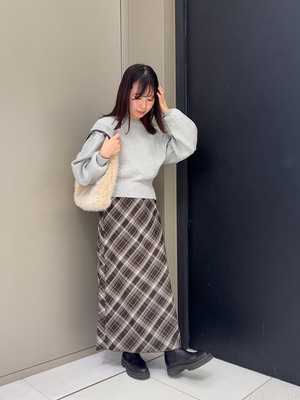 グレー系のニット/セーター、ブラウン系のスカート、ホワイト系のハンドバッグを着用したレディースの冬コーディネートの3枚目の写真