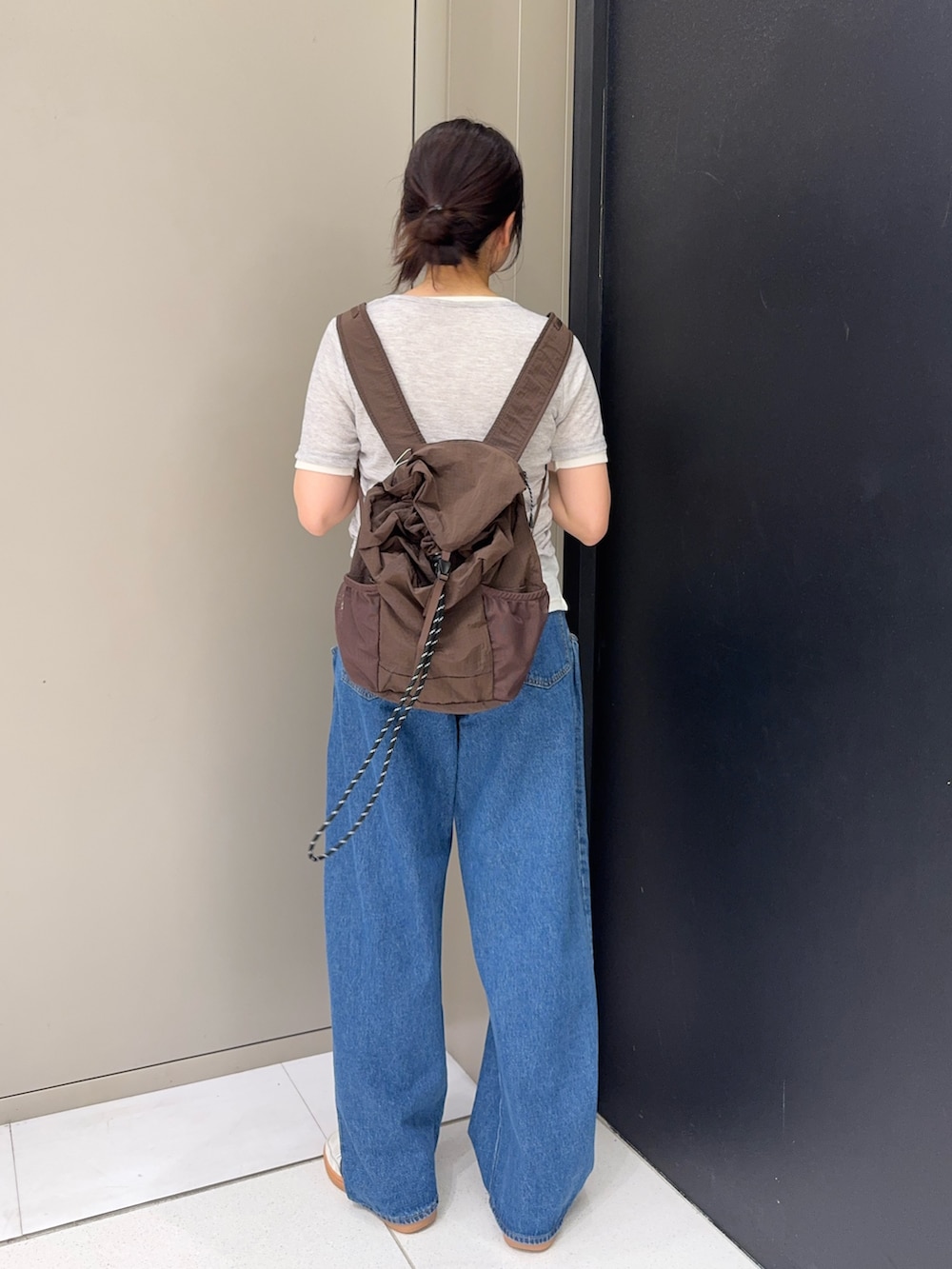 ブラウン系のバックパック/リュック、グレー系のTシャツ/カットソー、ブルー系のデニムパンツを着用したレディースの春コーディネートの3枚目の写真