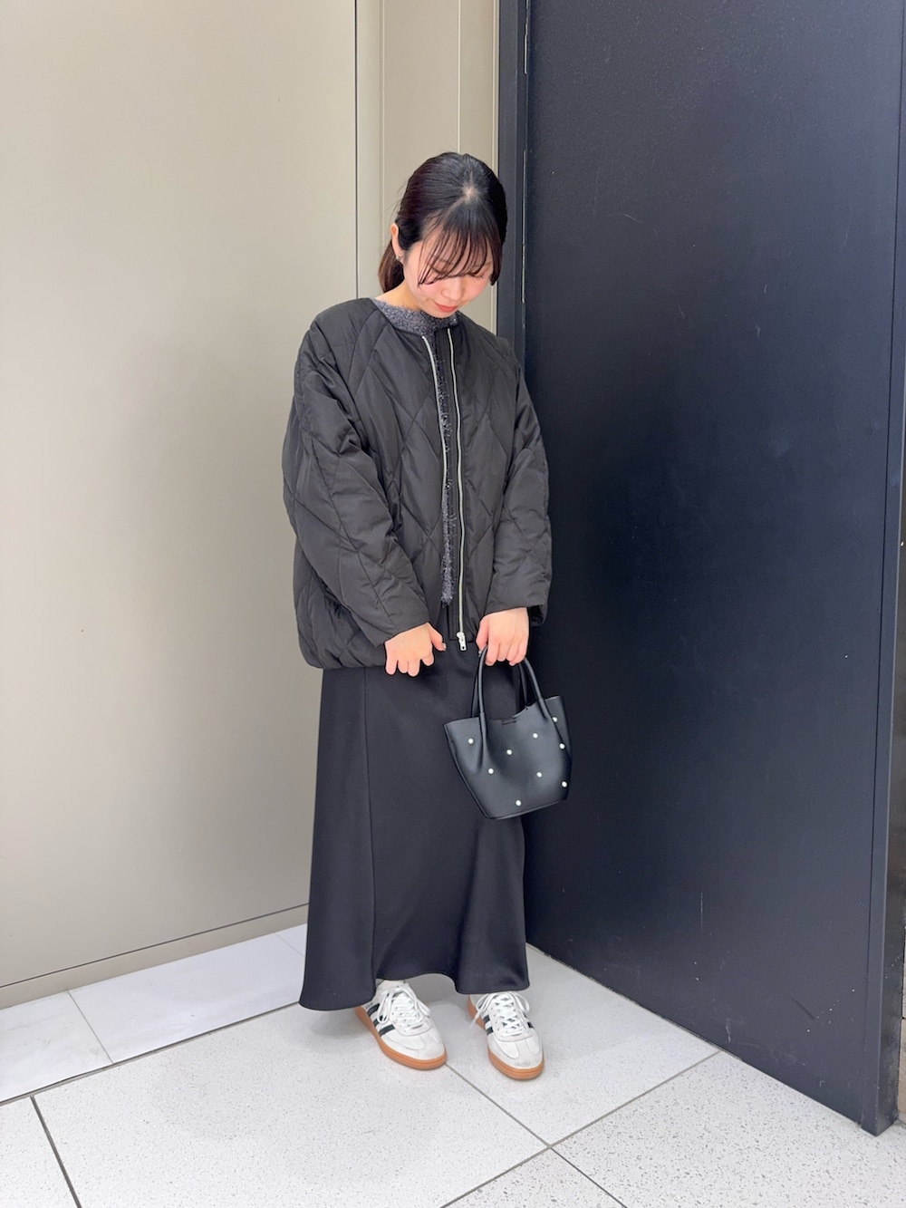 ブラック系のダウンジャケット/コート、ブラック系のスカート、ブラック系のハンドバッグを着用したレディースの冬コーディネートの3枚目の写真