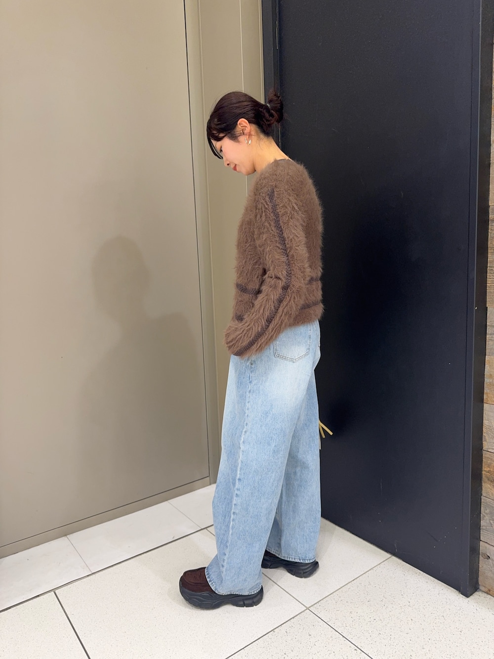 ブラウン系のニット/セーター、ベージュ系のショルダーバッグ、ブルー系のデニムパンツを着用したレディースの冬コーディネートの3枚目の写真